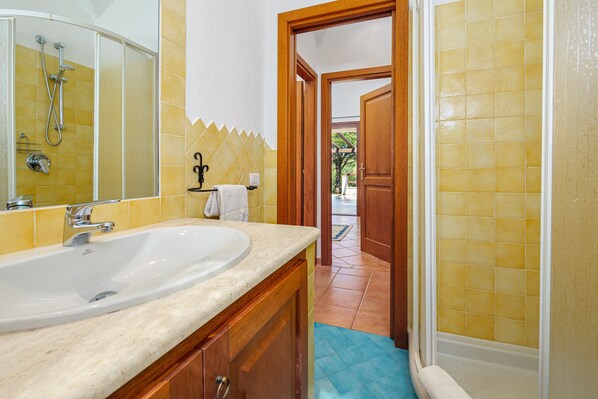 Ein Badezimmer mit einem großen Waschbecken, Dusche und einer Tür zu einem Außenbereich.