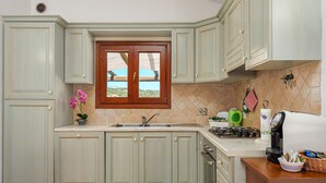 A kitchen with light green cabinets, a window with a view, a sink, a stove, and a coffee maker. - Holiday Home "Casa Relax Vista Mozzafiato" with Garden & A/C (Cannigione)