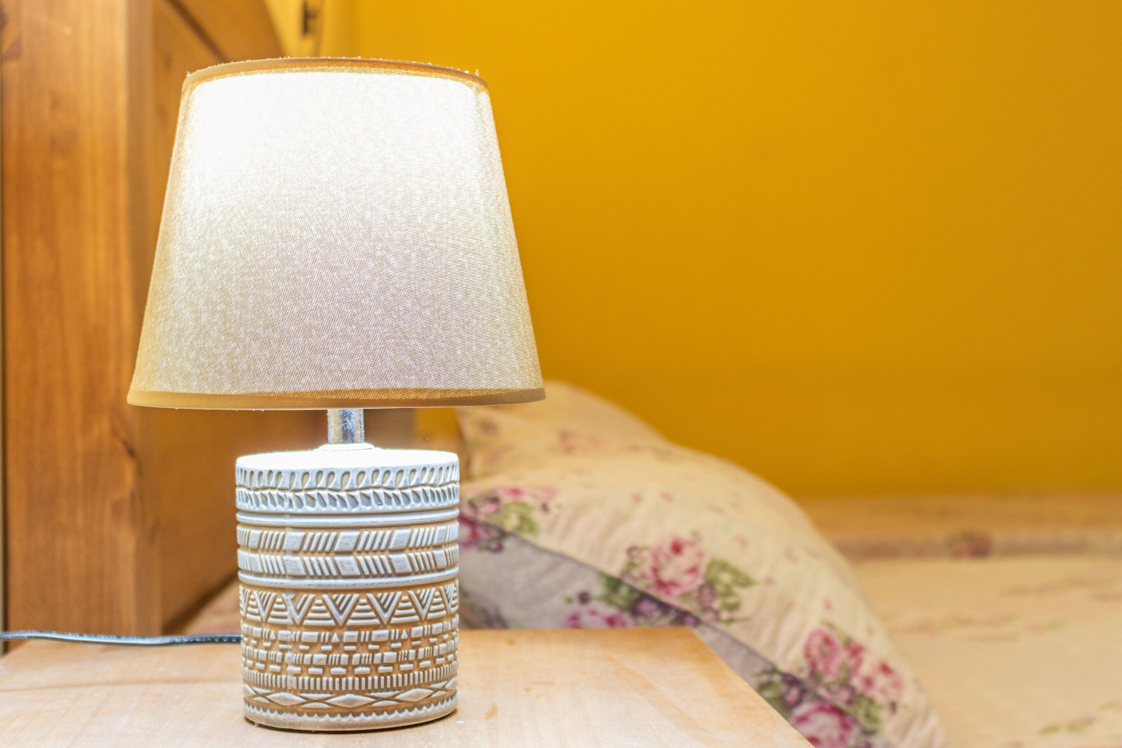 Une lampe dont le pied est décoré d’un motif, posée sur une surface en bois.