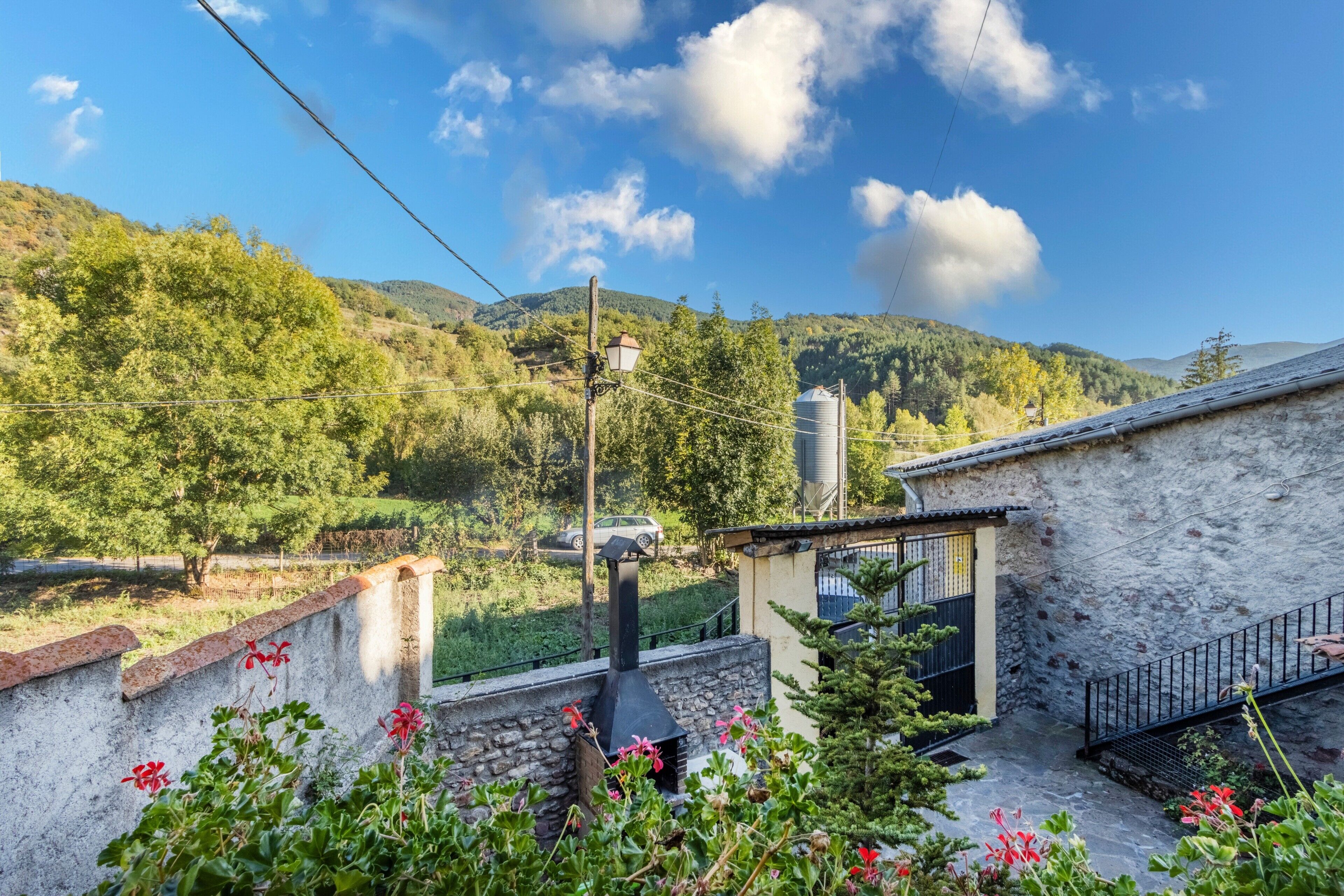 A stone building with a chimney, surrounded by greenery and a clear sky.