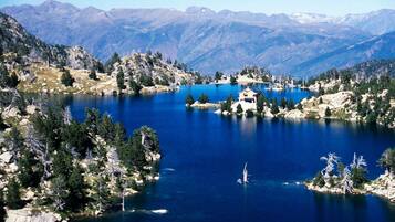 Un lago rodeado de montañas, una pequeña casa en una isla y densas áreas boscosas.