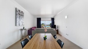Una sala moderna con una mesa de comedor, sofás y vistas al exterior.