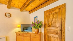 A room with a wooden cabinet, a television, a clock, and a wooden door.
