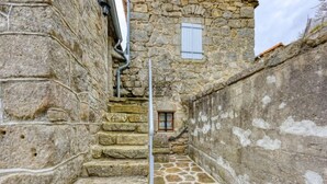 A narrow stone staircase leading to a small window with shutters.