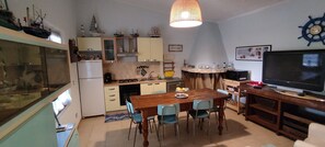 Cocina compacta con una mesa, sillas, un televisor y un adorno con forma de timón de barco.