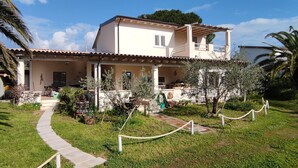 Un edifici de dues plantes amb teulada de rajola, un porxo cobert i un camí que condueix a l'entrada.