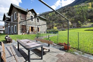 Una casa in pietra con una terrazza in legno, una panchina e un tavolo.