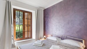 A bedroom with a large window, a bed with white linens, and a purple wall. - Apartment 'Casa Tua - Avise' with Mountain View, Private Terrace and Wi-Fi (Runaz)