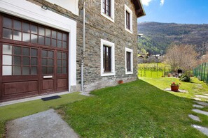 Un edificio in pietra con un garage e un prato ben curato.