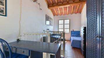 A room with a bed, a table, a chair, a window, and a door with a patterned design.