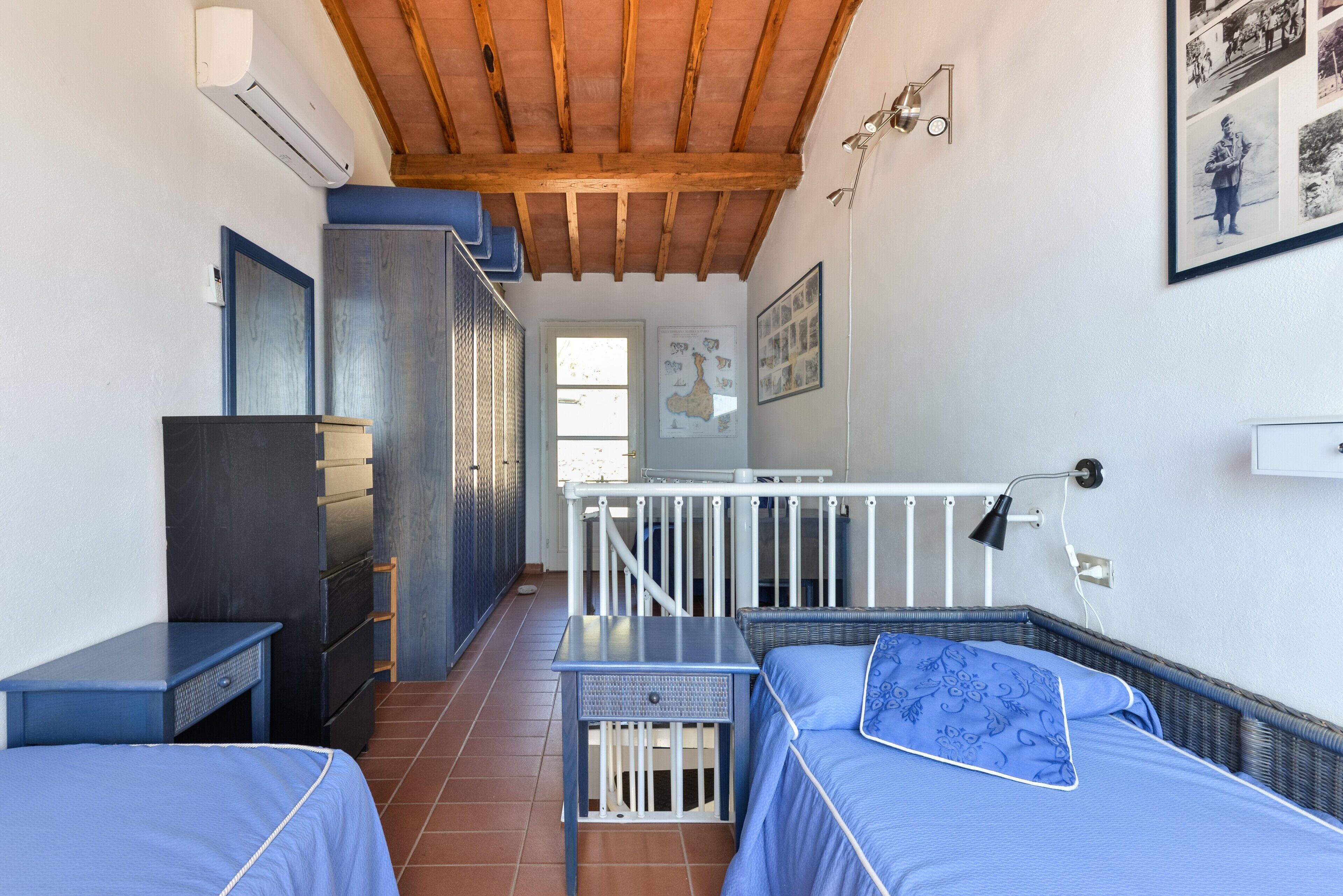Una habitación con dos camas, techo de madera, un mapa en la pared y una ventana.