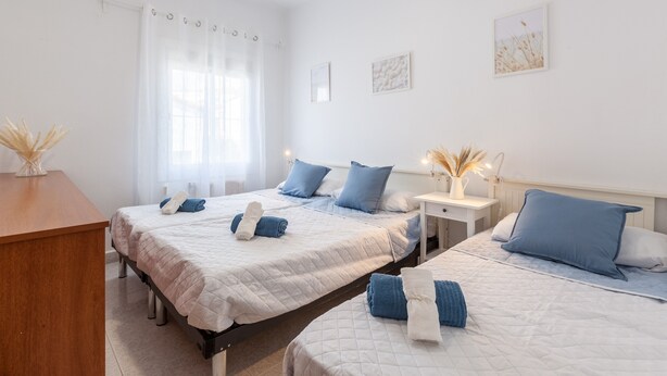 Hotellihuone, jossa on kaksi sänkyä, puinen työpöytä ja ikkuna, jossa on verhot.