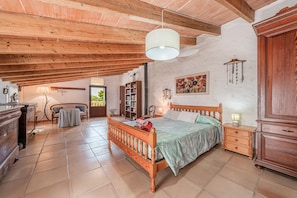 A bedroom with a wooden bed, a nightstand, a dresser, and a hanging light fixture.