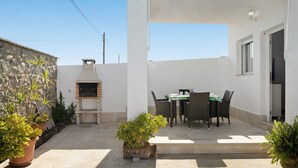 A patio with outdoor furniture, a barbecue grill, and potted plants.