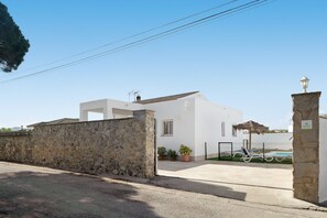 Un bâtiment blanc avec un mur en pierre, une piscine et un portail.