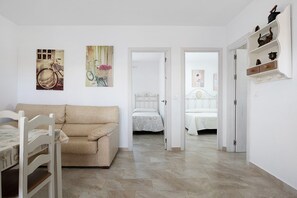 Una habitación con cama, una silla, una mesa y una puerta que da a otra estancia.