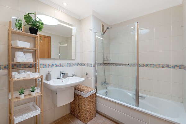 A bathroom with a glass-enclosed shower, a sink, a mirror, and a shelf with toiletries. - Vacation Home "Ático Beach Sotavento" with Shared Pool & Wi-Fi (Granadilla)