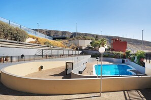 A swimming pool with a curved design, surrounded by a low wall and a fence.