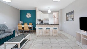 A modern living room with a sofa, a glass coffee table, and a dining area with chairs and a table. - Vacation Home "Vivienda Vacacional Atlántida" with 2 Shared Pools, 2 Private Terraces & Wi-Fi (Caletillas)