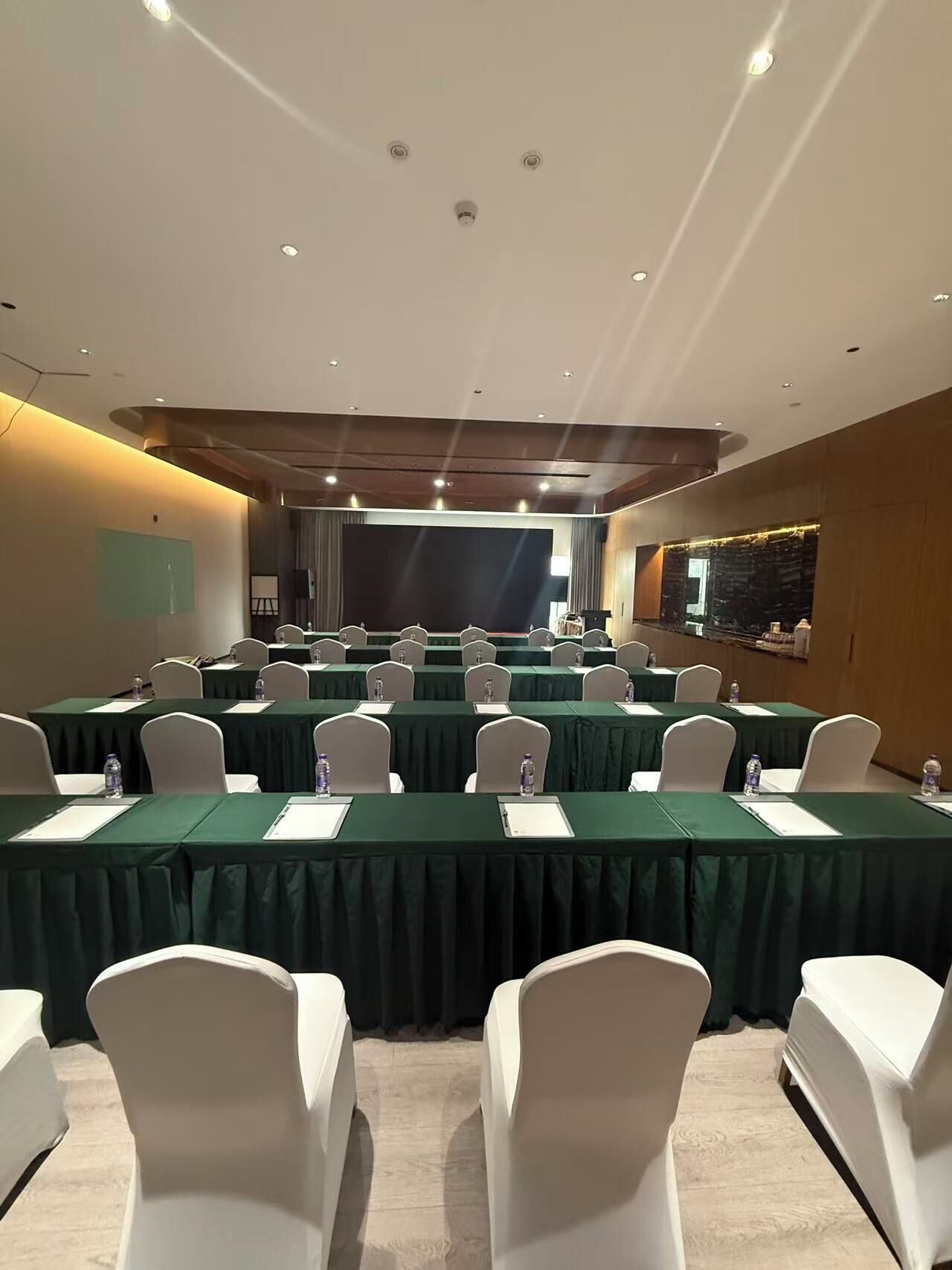 A conference room with multiple tables, chairs, and a stage.