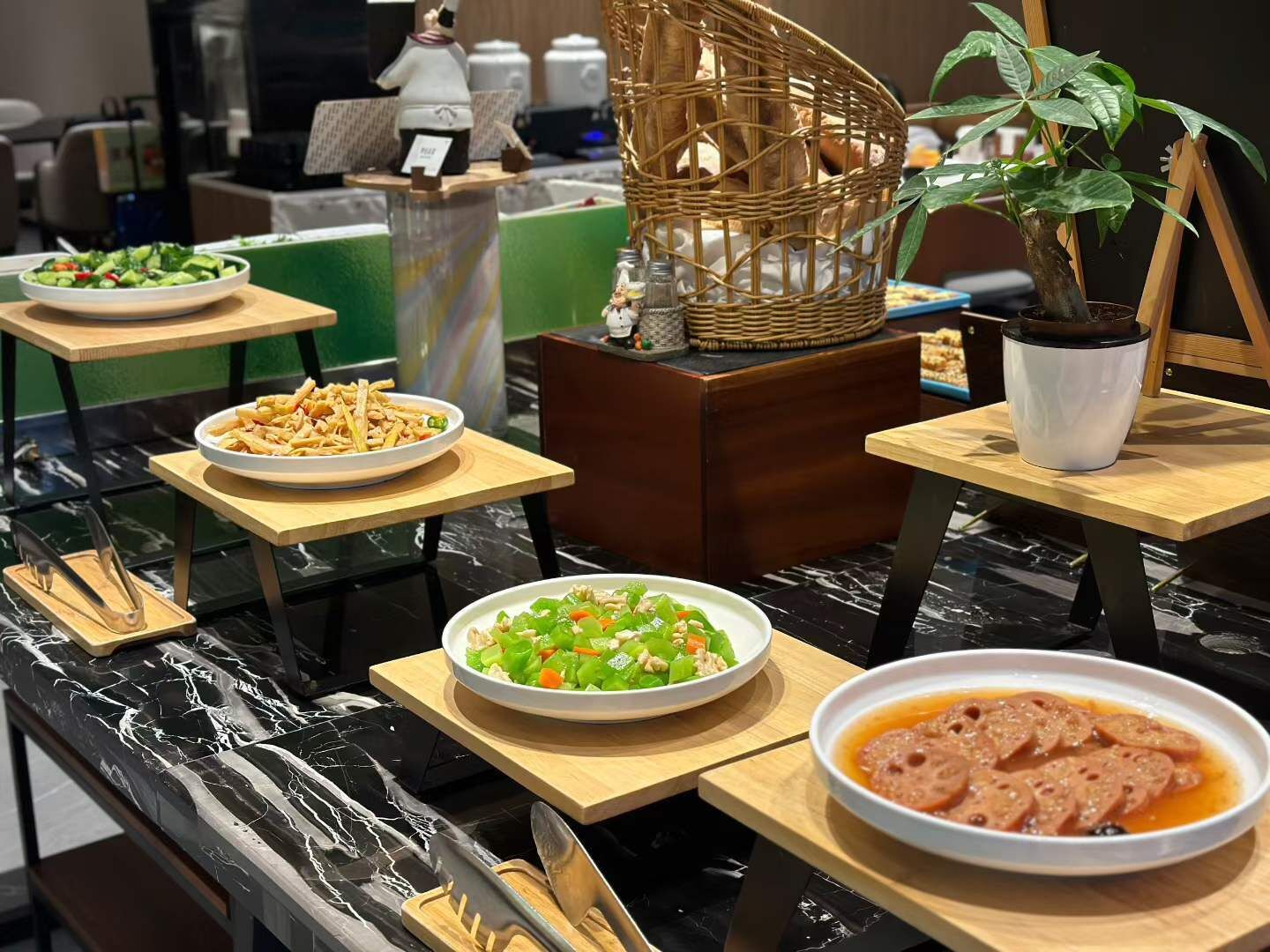 Un buffet garni de différents plats, un panier en osier, une plante en pot et une petite table avec un pot blanc.