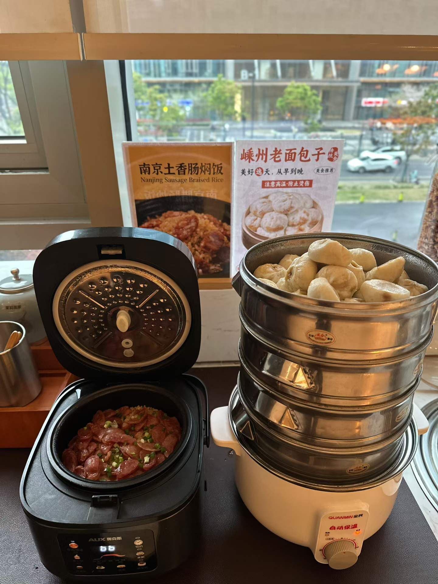 A kitchen with a slow cooker, a rice cooker, and a poster on the wall.