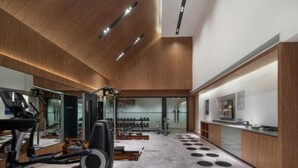 A gym with exercise equipment, a reception desk, and a large mirror. - UrCove by Hyatt Nanjing South Railway Station (Nanjing)