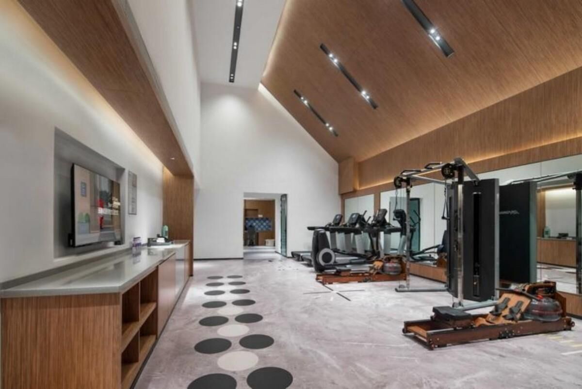 Un gimnasio moderno con equipo de ejercicio, un largo pasillo y una zona de recepción con mostrador.
