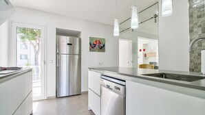 Une cuisine moderne dotée d’appareils électroménagers en acier inoxydable, d’un lave-vaisselle et d’un grand îlot central avec un évier.
