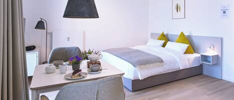 A modern bedroom with a bed, bedside table, and a desk with a chair.