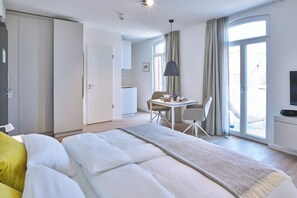 Una habitación de hotel moderna con cama, zona de comedor y televisión.