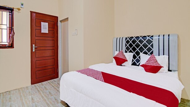 Una habitación de hotel con una cama grande, una puerta de madera y una ventana con barrotes.