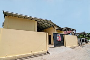 Un bâtiment doté d’un toit plat, d’une entrée fermée par un portail et surplombant un ciel dégagé.
