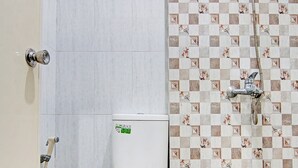 Un baño con inodoro, ducha y piso de baldosas.