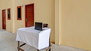 Una habitación con una cama individual, una puerta de madera y un ordenador portátil sobre una mesa.
