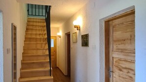Una scala in legno conduce a una piattaforma con una porta sulla destra.