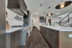 A modern kitchen with dark cabinetry, a white countertop, and pendant lighting.