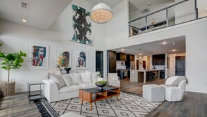 A spacious living area with a white sofa, a coffee table, and artwork on the walls. - Penthouse w Rooftop, Private Chef, Secure Parking (Atlanta)