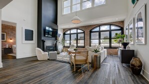 A spacious living room with a fireplace, large windows, and a modern design. - Penthouse w Rooftop, Private Chef, Secure Parking (Atlanta)