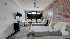 A modern bedroom with a large bed, a desk, and a TV. - Penthouse w Rooftop, Private Chef, Secure Parking (Atlanta)