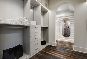 A modern, minimalist bathroom with a wooden floor, a towel rack, a vanity with drawers, and a mirror.