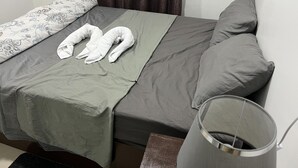 Un lit avec une literie grise, deux oreillers et deux serviettes disposées sur le lit.