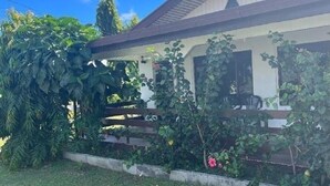 Une maison dotée d’un porche abrité, entourée d’une végétation luxuriante et d’une pelouse bien entretenue.