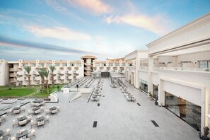 Un patio de hotel con mobiliario exterior, una escalera central y varios balcones.