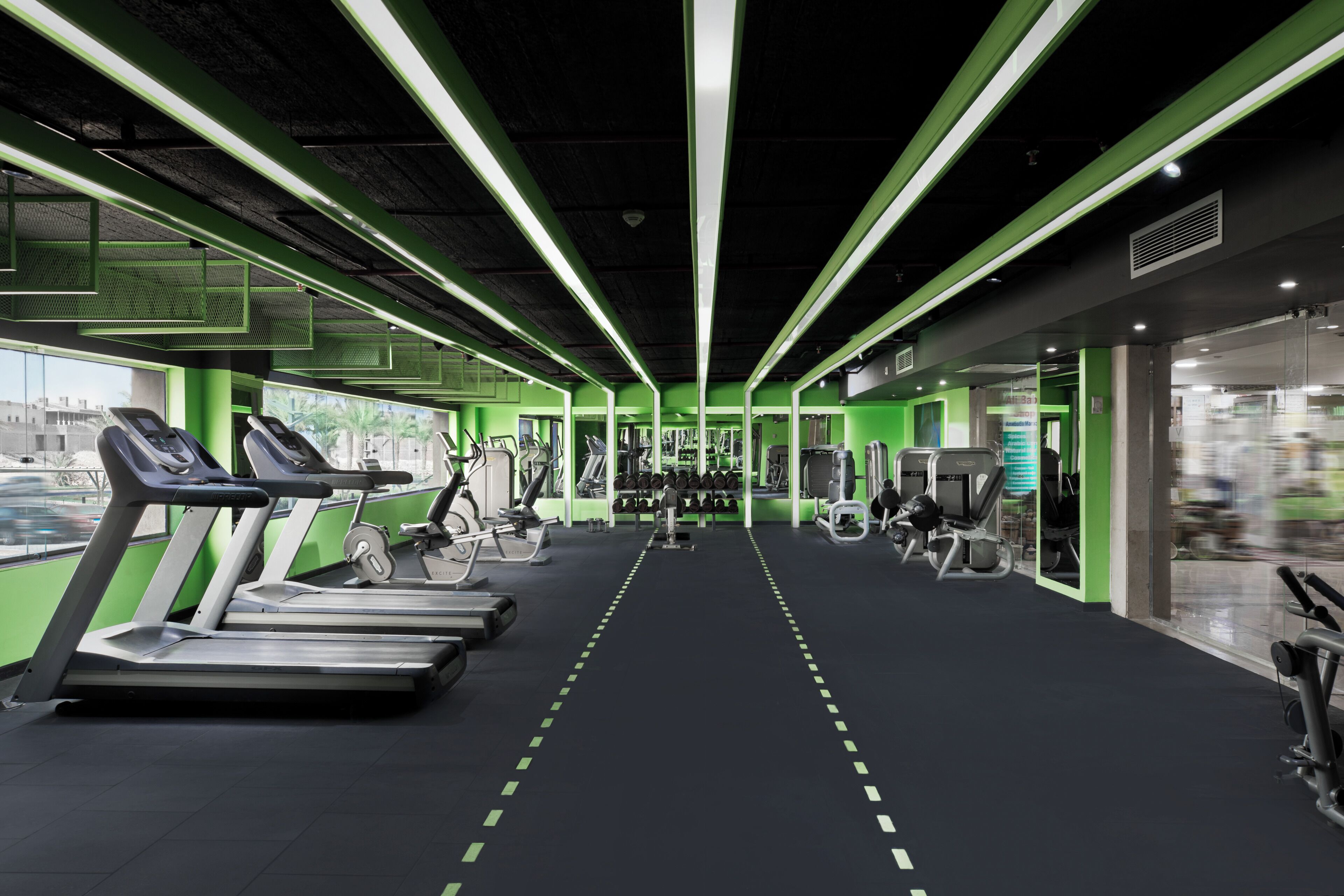 Une salle de sport équipée de tapis de course, d’appareils de musculation et d’un mur recouvert de miroirs.