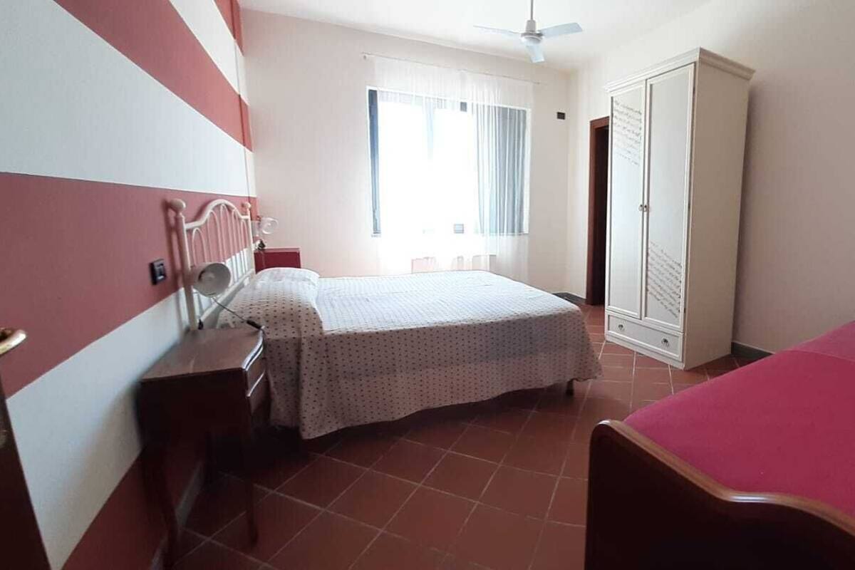 A bedroom with a bed, a wardrobe, a desk, and a chair.