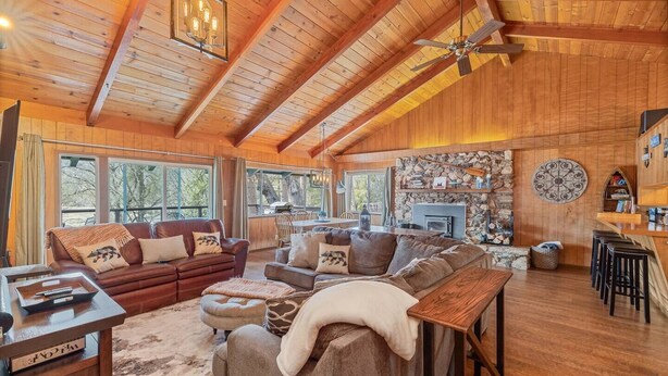 Ein geräumiges Wohnzimmer mit hohen Decken, Holzbalken, Kamin und Steinwand.