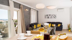 Un coin repas avec une table dressée pour deux personnes, un canapé et un balcon offrant une vue agréable.