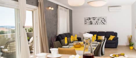 A dining area with a table set for two, a sofa, and a balcony with a view.