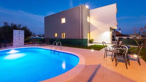 Un bâtiment moderne doté d’une piscine et d’un espace extérieur aménagé pour se détendre.